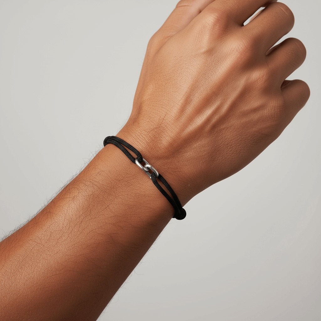 Hand wearing a black bracelet on a plain background