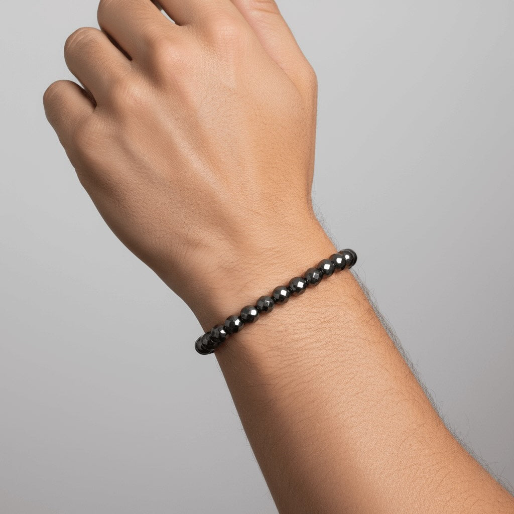 Hand wearing a black beaded Velmont bracelet on a gray background