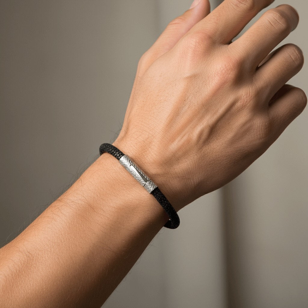 Hand wearing a black and silver Velmont bracelet on a neutral background