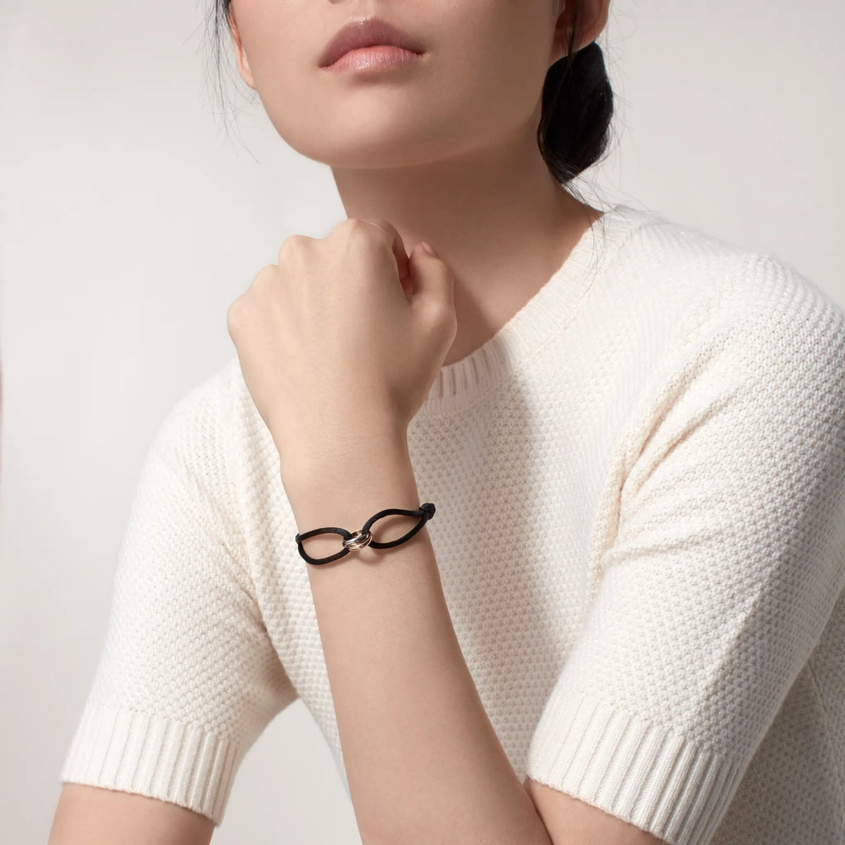 Person wearing a black bracelet on a plain background