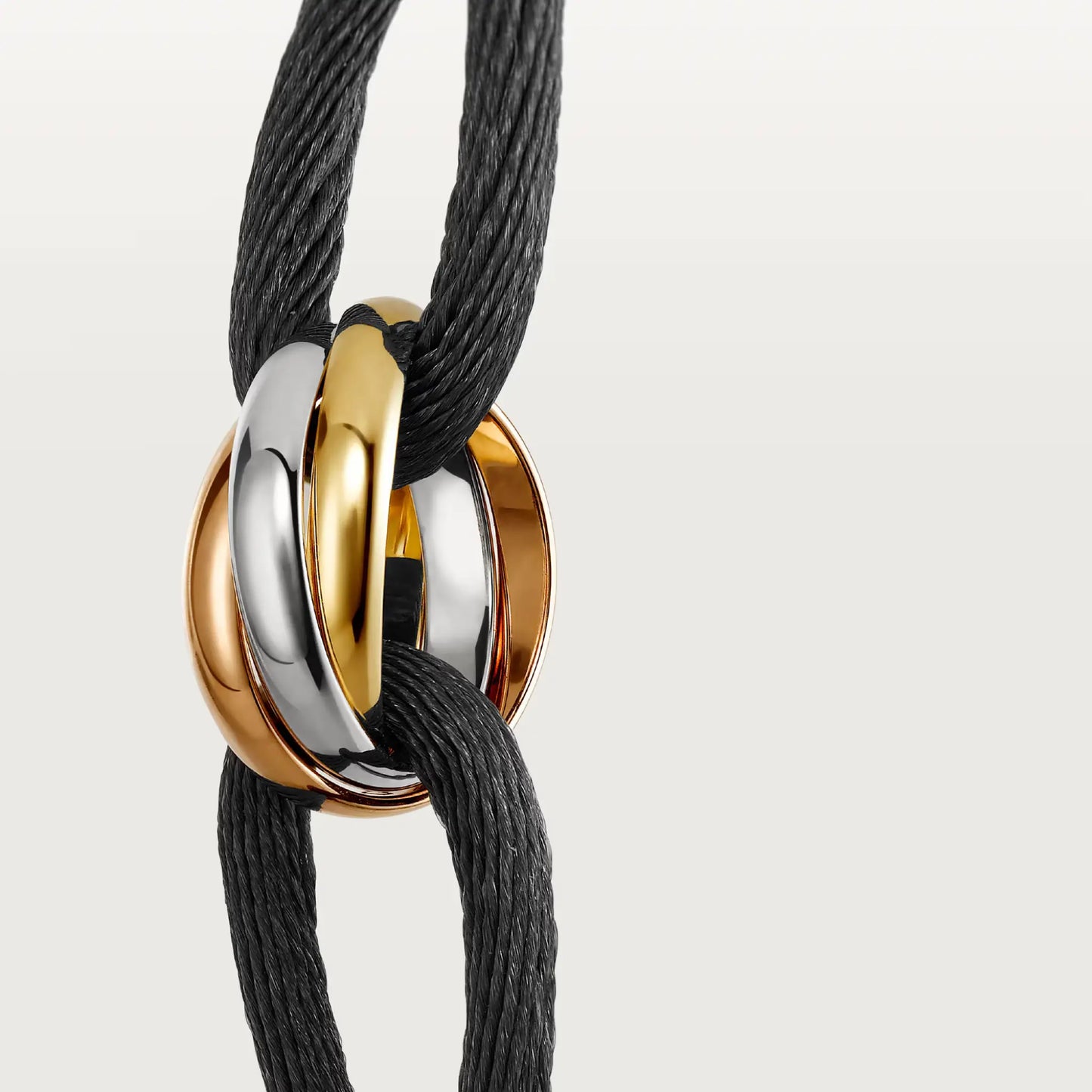 Bracelet with gold, rose gold and silver circular rings on a black cord against a light gray background