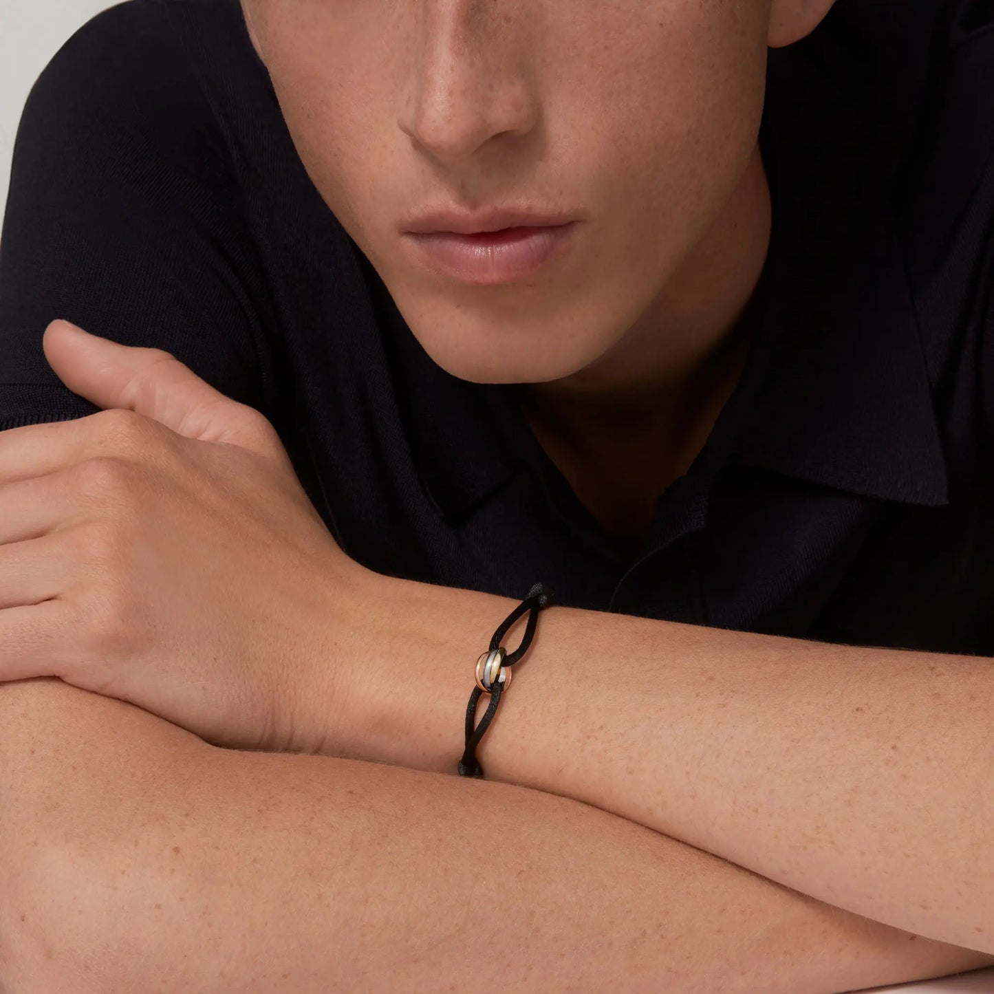 Person wearing a black braided bracelet on a neutral background