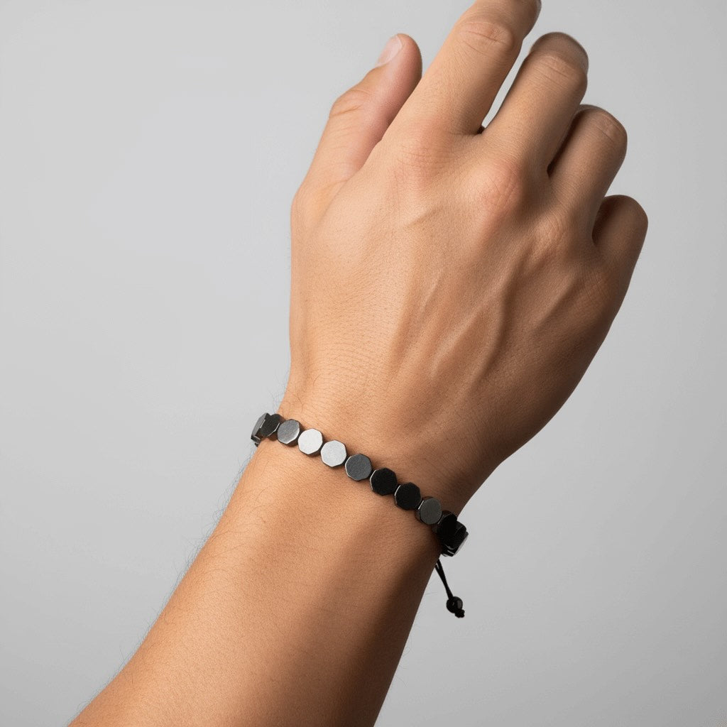 Hand wearing a Velmont bracelet with black and silver beads on a gray background